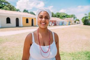 gelukkige braziliaanse vrouw gekleed in traditioneel bahiaans kostuum, in het historische centrum van porto seguro op de achtergrond foto