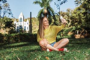 mooie vrouw die selfie neemt met haar smartphone op het platteland. kerk op de achtergrond. foto