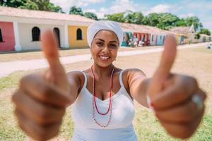 gelukkige braziliaanse vrouw gekleed in traditioneel bahiaans kostuum, met duimen omhoog in het historische centrum van porto seguro foto