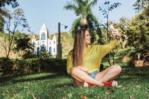 mooie vrouw die selfie neemt met haar smartphone op het platteland. kerk op de achtergrond. foto