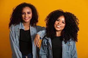 twee jonge Afro-Amerikaanse vrouwen met krullend haar camera kijken en glimlachen. schattige afro meisjes met krullend haar glimlachend camera kijken. foto