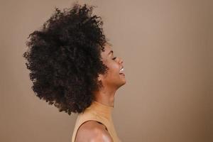 kant een lachende jonge latin afro vrouw. vreugde, positief en liefde. mooi afrikaans kapsel. pastel studio achtergrond. foto