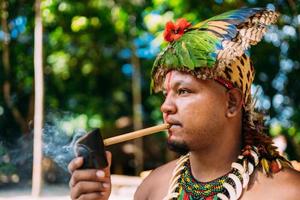 indisch opperhoofd van de pataxo-stam rookpijp. braziliaanse indiaan met veren hoofdtooi en ketting foto