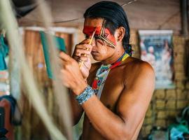 indiaan van de pataxo-stam, met behulp van een spiegel en schminken. foto