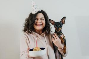 gelukkig jong meisje dat zelfgemaakte cake geeft aan haar hond, binnenshuis foto