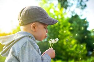 schattig kind blaast paardebloem foto