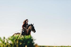 jong meisje galopperen op een jong donker paard. foto