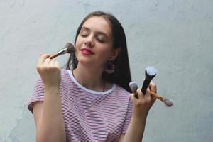 portret van een jong meisje dat haar make-up doet met make-upborstels, beautyblogger foto