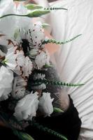 witte bloemen, boeket op een wit laken, zwarte beentattoo foto