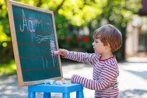 kleine jongen op schoolbord het beoefenen van wiskunde