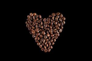 koffiebonen in de vorm van een hart. koffie op een zwarte achtergrond. bovenaanzicht. macro foto