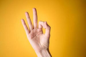 vrouw hand toont gebaar oke op gele achtergrond foto