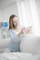 jonge vrouw met behulp van een digitale tablet op een sofa foto