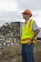 arbeider die zich dichtbij vrachtwagen stortend afval bevindt bij stortplaats