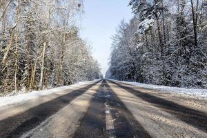 smalle besneeuwde winterweg foto