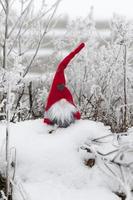 een klein speeltje zittend in de sneeuw in rode kleren foto