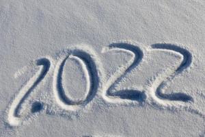 de inscriptie over het nieuwe jaar 2022 op de sneeuw in de winter foto