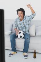voetbalfan juichen terwijl u tv kijkt foto