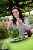 vrolijke jonge vrouw salade serveren op barbecue feest buiten