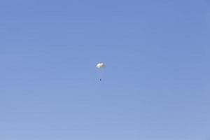 een parachutist die afdaalt in de blauwe lucht foto