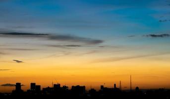 geeft een warm gevoel, zonsondergang achter het stadsgebouw, silhouet hoge gebouwen in de stad, silhouet opnieuw bouwen mooie hemelachtergrond en vrijheidsconcept. foto