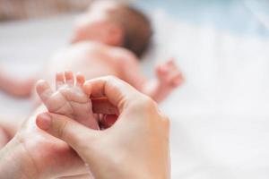 de voet van een baby wordt door zijn moeder gemasseerd foto