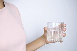 close-up van de hand van een jonge vrouw die een drinkglas vasthoudt. foto