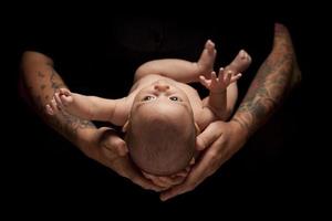 handen van vader en moeder houden pasgeboren baby op zwart