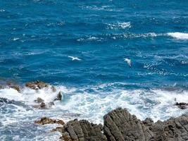 blauwe zee die wit schuim achterlaat bij het beuken tegen de golven foto