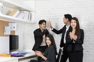 gelukkig business team applaudisseren. zakenmensen werken samen aan project en brainstormen op kantoor. vriendelijke diverse medewerkers feliciteren zakenvrouw met zakelijke prestatie. foto