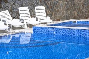 zwembad met blauwe watertrap voor afdaling en beklimming in het water. de ligstoelen staan leeg bij het zwembad. foto