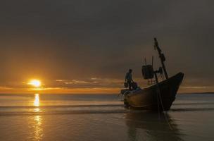 silhouet visser op de boot op het strand. foto