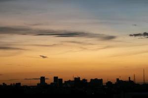 geeft een warm gevoel, zonsondergang achter het stadsgebouw, silhouet hoge gebouwen in de stad, silhouet opnieuw bouwen mooie hemelachtergrond en vrijheidsconcept. foto