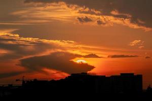 geeft een warm gevoel, zonsondergang achter het stadsgebouw, silhouet hoge gebouwen in de stad, silhouet opnieuw bouwen mooie hemelachtergrond en vrijheidsconcept. foto