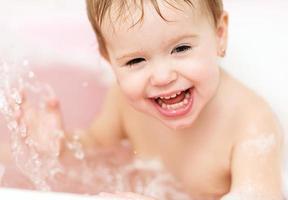 gelukkig babymeisje lachen en badend in bad foto