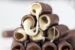 melkvulling stroomt uit wafelbuizen in chocolade foto