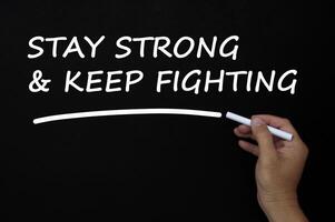 blijf sterk en blijf vechten tegen tekst die op het bord is geschreven met krijt. foto
