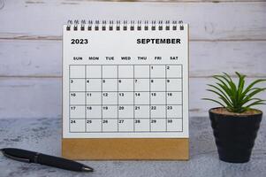 september 2023 bureaukalender met tafelplant en pen. foto