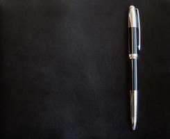 elegante metalen pen op zwart leer achtergrond foto