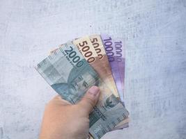 een man met een bankbiljet met een nominale waarde van 10000, 5000, 2000 rupiah in Indonesische valuta foto