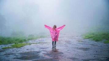 toerist met roze regenjasstandaard bekijk het landschap natuurlijke mooie aanrakingsmist in phu hin rong kla nationaal park. reizen natuur, reizen ontspannen, reizen thailand, regenseizoen. foto