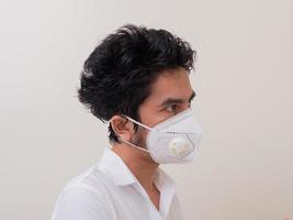 Aziatische jongeman in wit overhemd en medisch masker om covid-19 te beschermen foto