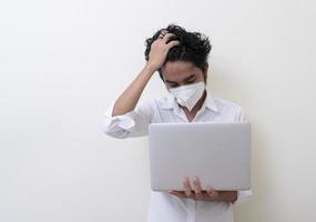 zakenman met medisch gezichtsmasker werkt thuis op laptop foto