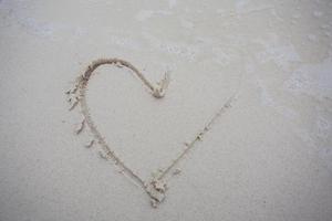 harten getekend op het zand van een strand foto