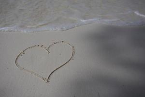 harten getekend op het zand van een strand foto