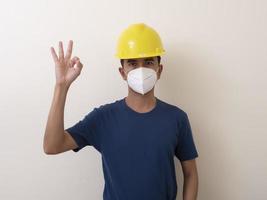 Aziatische industriële arbeiders dragen gele helmen, dragen beschermende maskers voor hun gezondheida foto