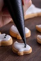 close-up van het versieren van schattige halloween-spookkoekjes met glazuur. foto