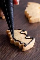 close-up van het versieren van schattige halloween vleermuis suiker koekjes met glazuur. foto
