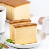 castella kasutera - mooie heerlijke Japanse gesneden biscuit eten op witte plaat over rustieke witte houten tafel, close-up, kopieer ruimte ontwerpconcept. foto