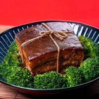 dong po rou dongpo varkensvlees in een mooie blauwe plaat met groene broccoli groente, traditionele feestelijke gerechten voor chinees nieuwjaar keuken maaltijd, close-up. foto